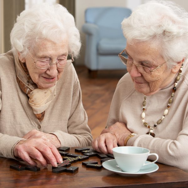 Two senior women playing dominoes at day care center